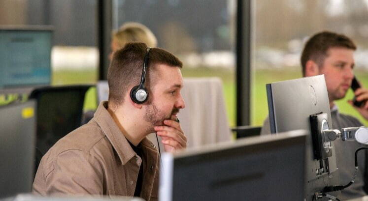 Highways recruitment consultant at desk on phone headset happy